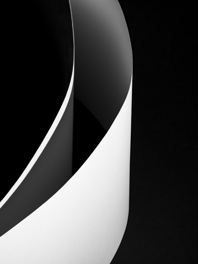 Een minimalistisch spel van licht en schaduw, waarin gebogen witte vlakken contrasteren met een diepe zwarte achtergrond. De zachte rondingen en scherpe randen creëren een sculpturale compositie, waarbij eenvoud en elegantie samenkomen. Deze abstracte studie van vorm en licht is vastgelegd in Amsterdam door Jasper Mulder.