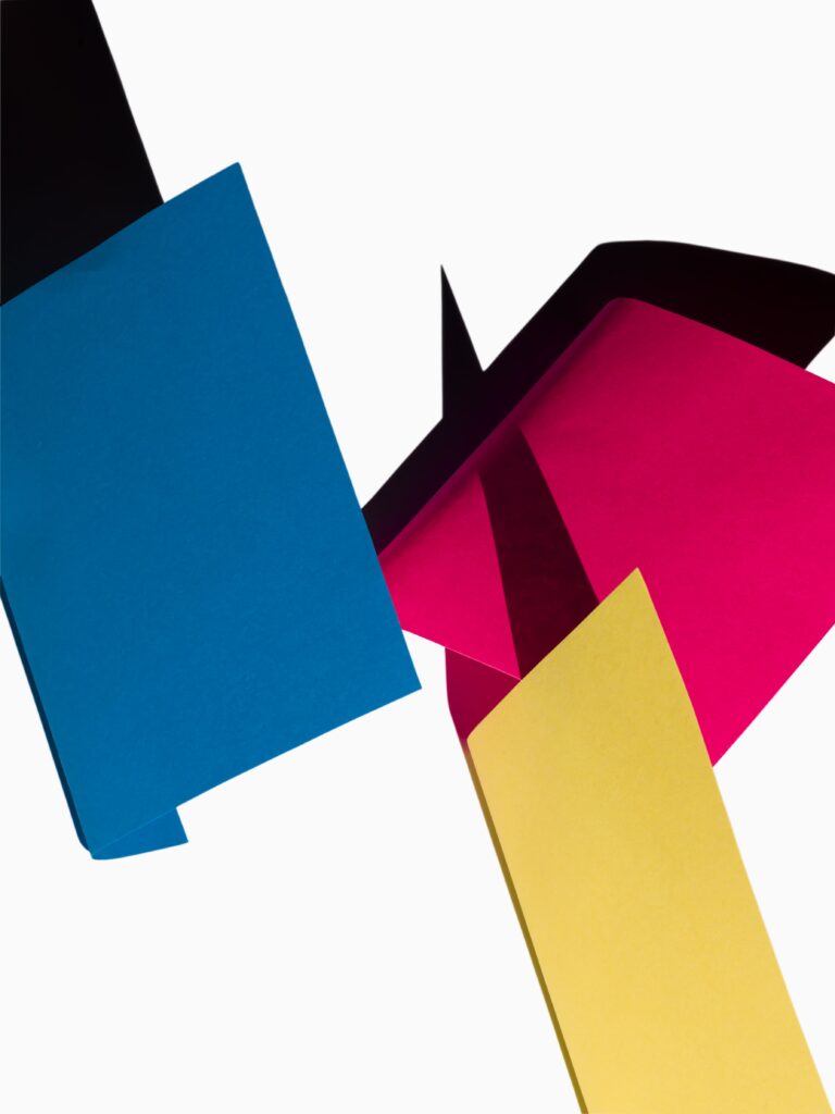 Een grafische compositie van gekleurde vlakken en schaduwen, waarin blauwe, rood en gele vormen elkaar dynamisch kruisen. Het contrast tussen licht en donker benadrukt de strakke lijnen en geometrische structuren, waardoor een abstract beeld ontstaat. De scherpe belichting en minimalistische opzet geven de foto een moderne, kunstzinnige uitstraling. Vastgelegd in Amsterdam door Jasper Mulder.