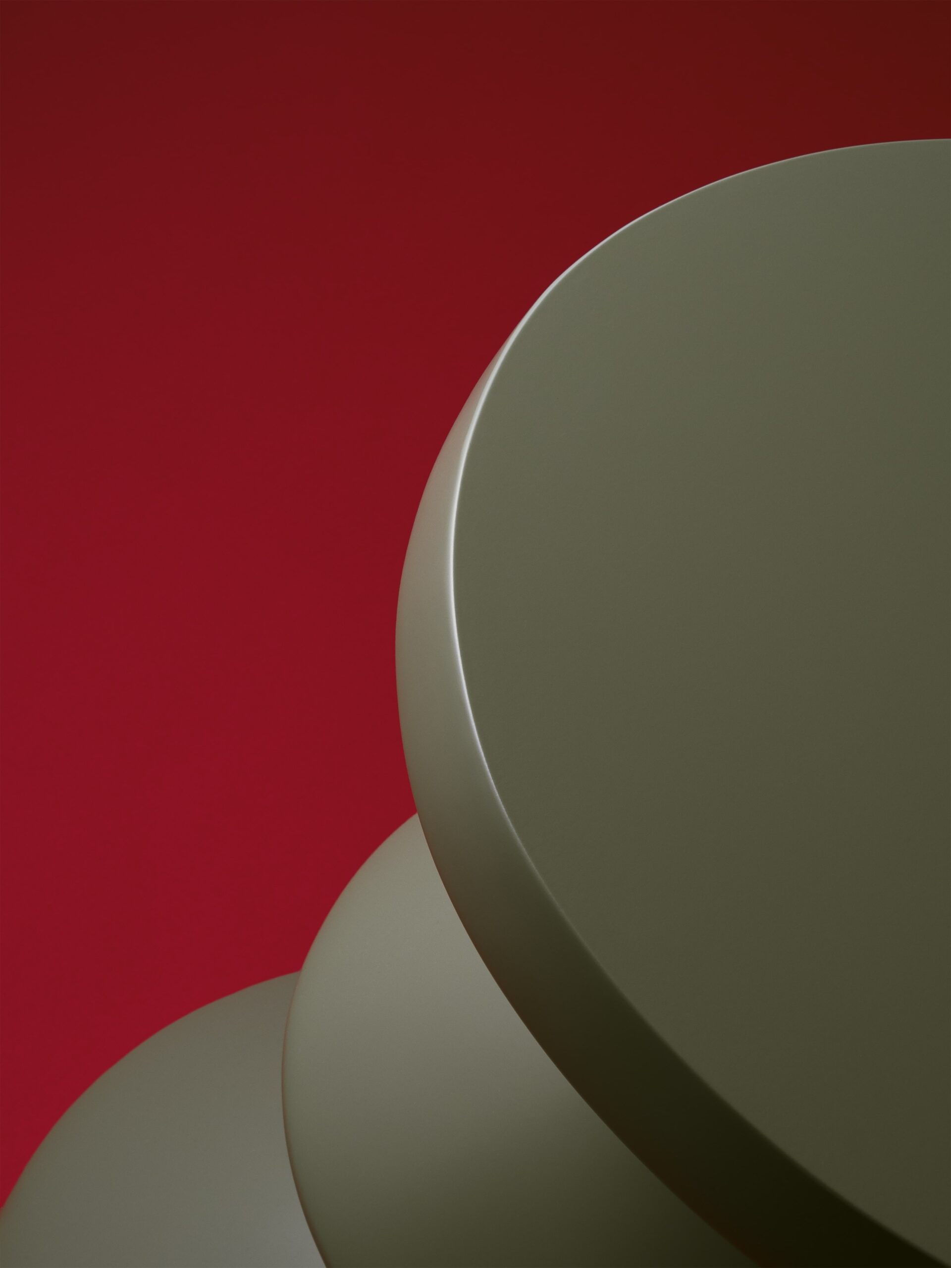 Close-up productfoto van een olijfgroene, moderne en abstracte kruk van Polspotten, een meubelwinkel in Amsterdam. De glanzende, ronde vormen van het designmeubel worden benadrukt door een contrasterende rode achtergrond. De productfotografie is verzorgd door Jasper Mulder en legt de subtiele details en het luxe karakter van de afwerking vast