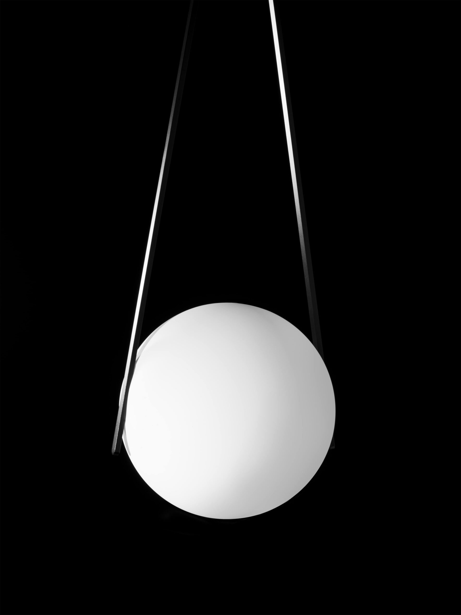 Minimalistische productfoto van een designlamp uit de collectie van Moooi. De witte bolvormige lamp hangt in een strakke, geometrische constructie tegen een diepzwarte achtergrond. Dit beeld speelt met licht en schaduw en benadrukt de moderne, abstracte esthetiek van de lamp. Een stijlvol voorbeeld van productfotografie, vastgelegd in Amsterdam door Jasper Mulder.