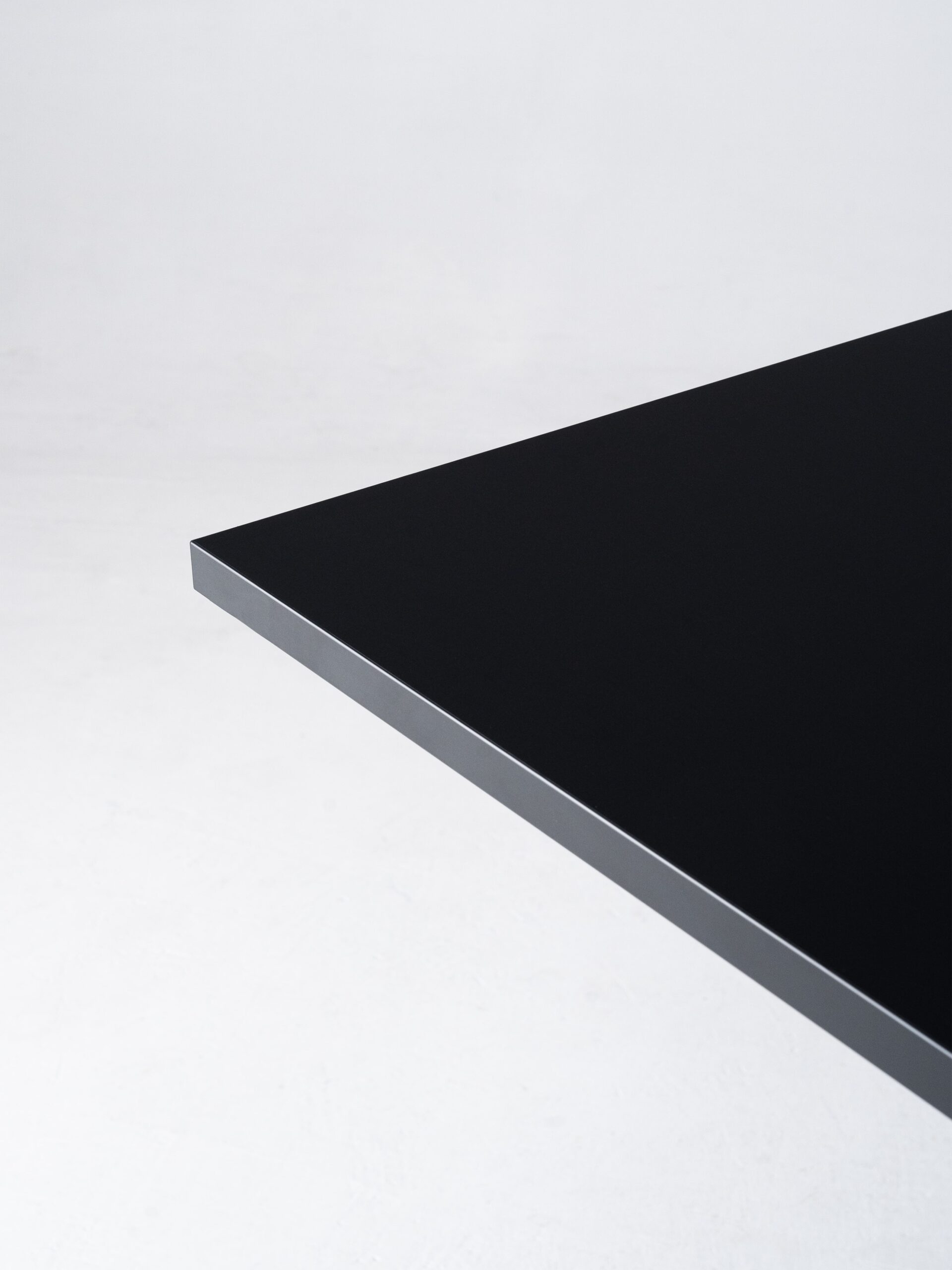 Minimalistische en abstracte productfoto van een zwart tafelblad, vastgelegd tegen een witte achtergrond. De scherpe lijnen en het contrast tussen de materialen benadrukken het strakke en moderne design. De productfotografie is professioneel uitgevoerd door Jasper Mulder om de hoogwaardige afwerking van het meubelstuk te tonen. Het product is van J. Kisch & Zonen, een gerenommeerd meubelmerk uit Amsterdam.