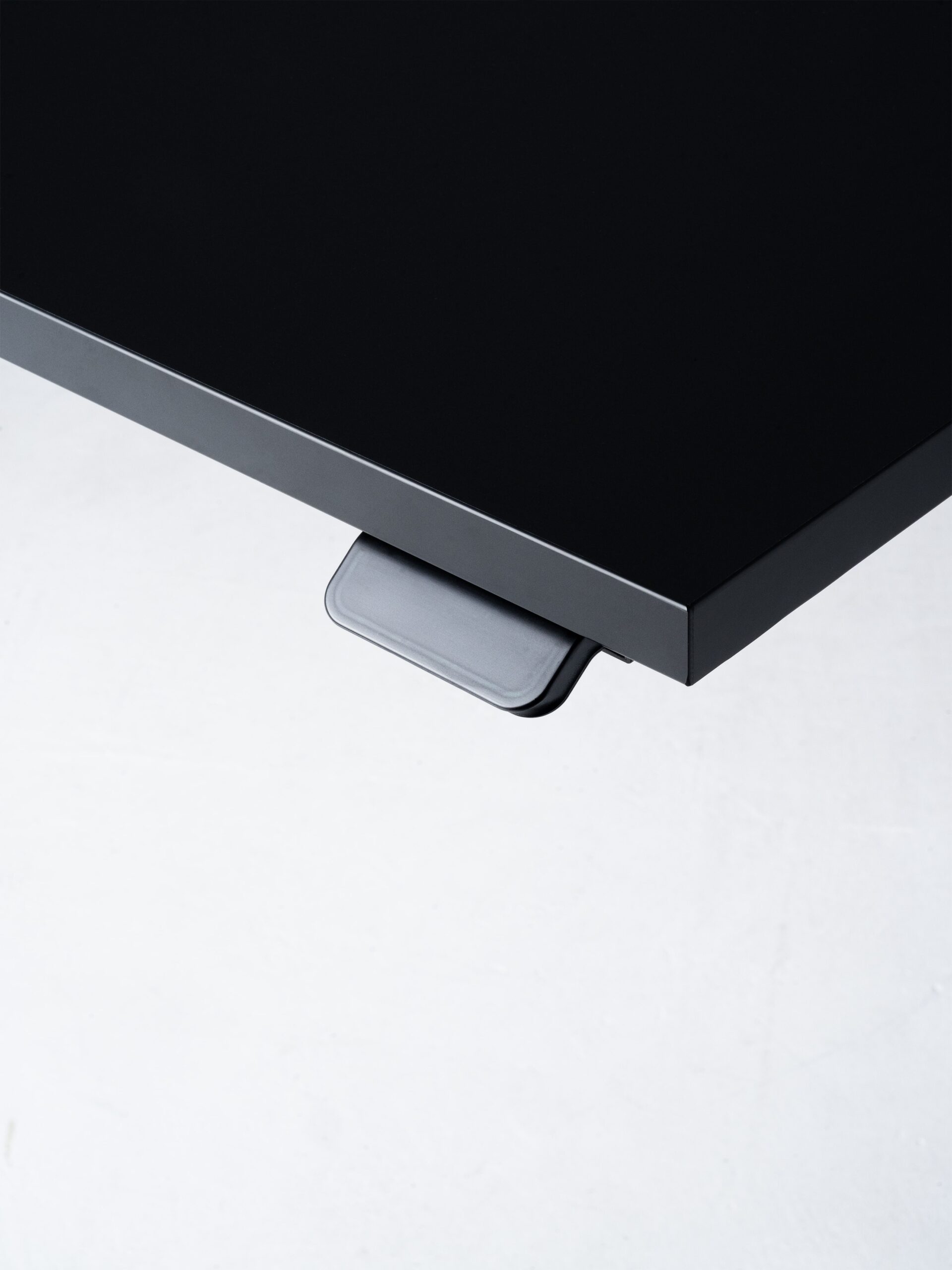Minimalistische productfoto van een zwart tafelblad met een geïntegreerd bedieningspaneel, vastgelegd tegen een lichte achtergrond. De scherpe lijnen en het contrast tussen de materialen benadrukken het strakke en functionele design. De productfotografie is professioneel uitgevoerd door Jasper Mulder om de hoogwaardige afwerking en het slimme ontwerp van het meubelstuk te tonen. Het product is van J. Kisch & Zonen, een gerenommeerd meubelmerk uit Amsterdam.