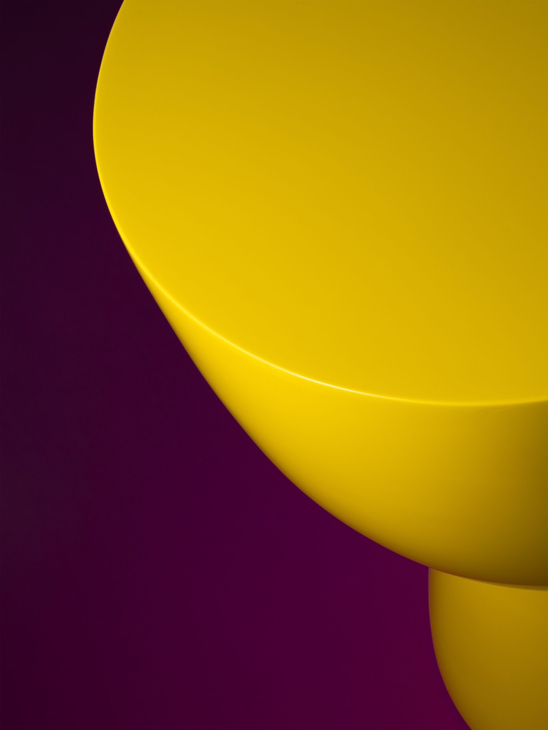 Close-up productfoto van een felgele, moderne en abstracte kruk van Polspotten, een meubelwinkel in Amsterdam. De glanzende afwerking en vloeiende rondingen worden geaccentueerd door het contrast met de diepe paarse achtergrond. De productfotografie is verzorgd door Jasper Mulder en legt de details en vorm van het designmeubel sfeervol vast.