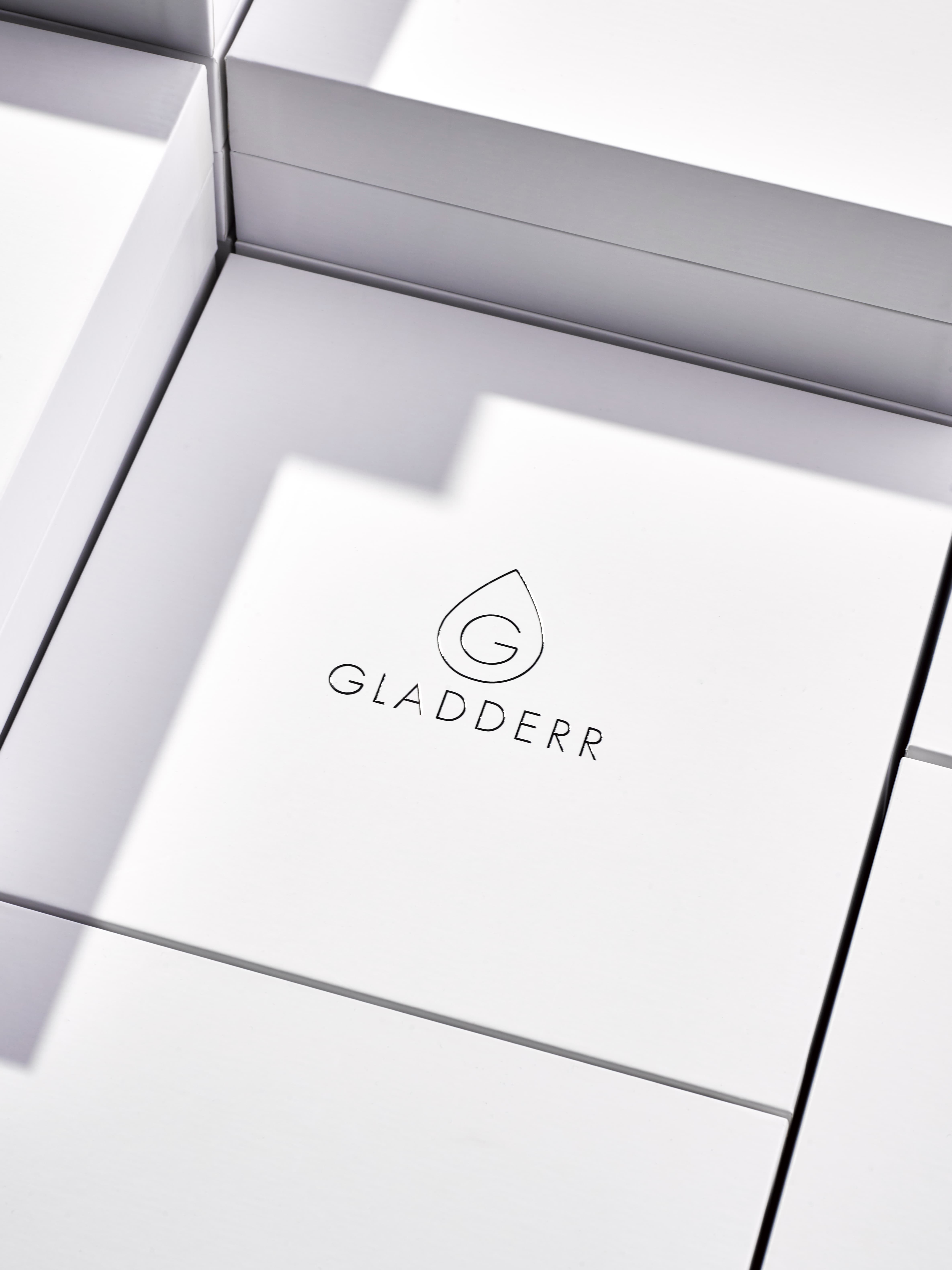 Premium scheerset van Gladderr met witte doos en logo, inclusief GLADDER GÉL, metalen scheermes met grip, en stijlvolle accessoires in een strak wit tray — minimalistisch en verfijnd design voor hoogwaardige grooming.