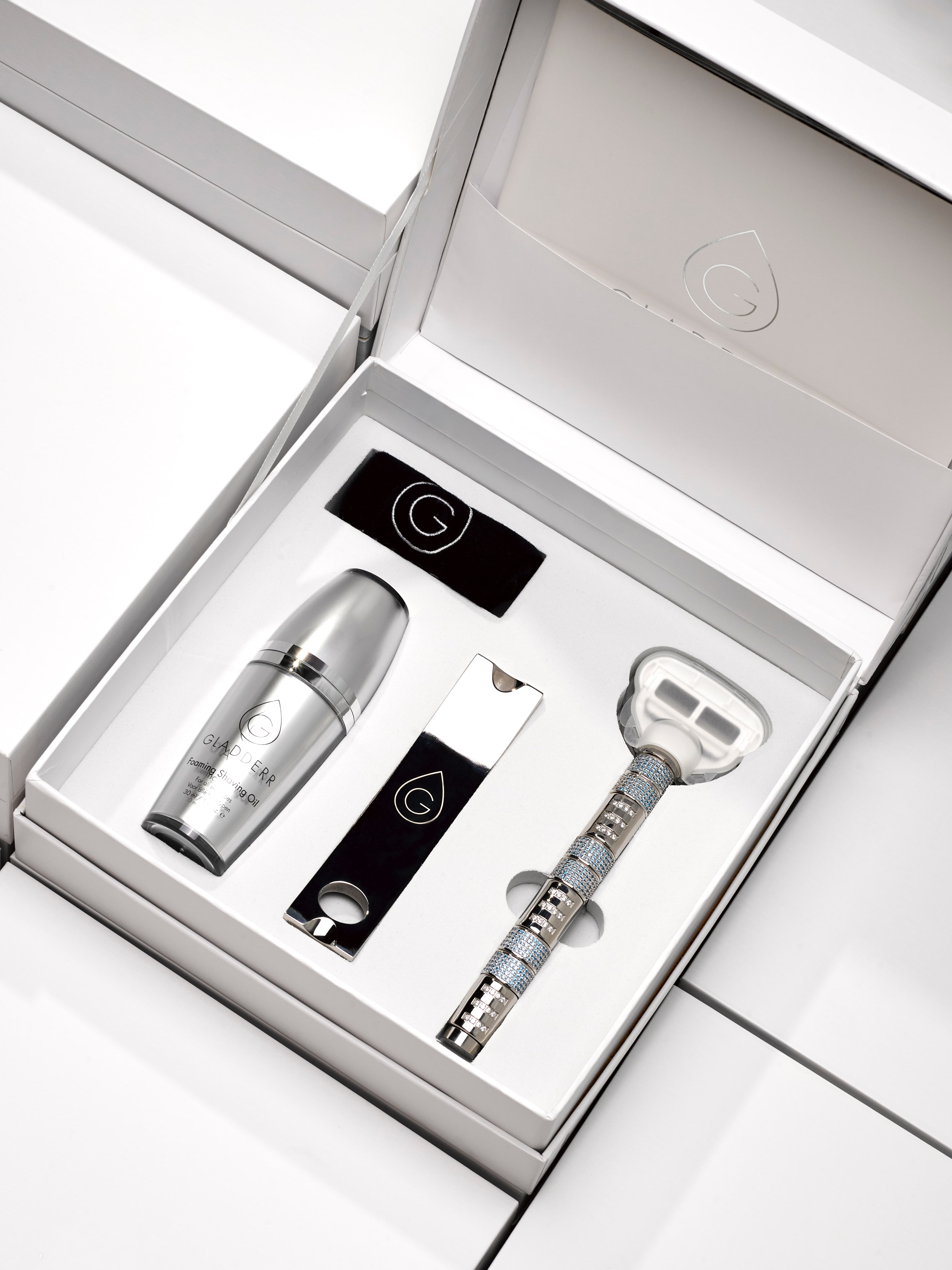 Premium scheerset van Gladderr met witte doos en logo, inclusief GLADDER GÉL, metalen scheermes met grip, en stijlvolle accessoires in een strak wit tray — minimalistisch en verfijnd design voor hoogwaardige grooming.