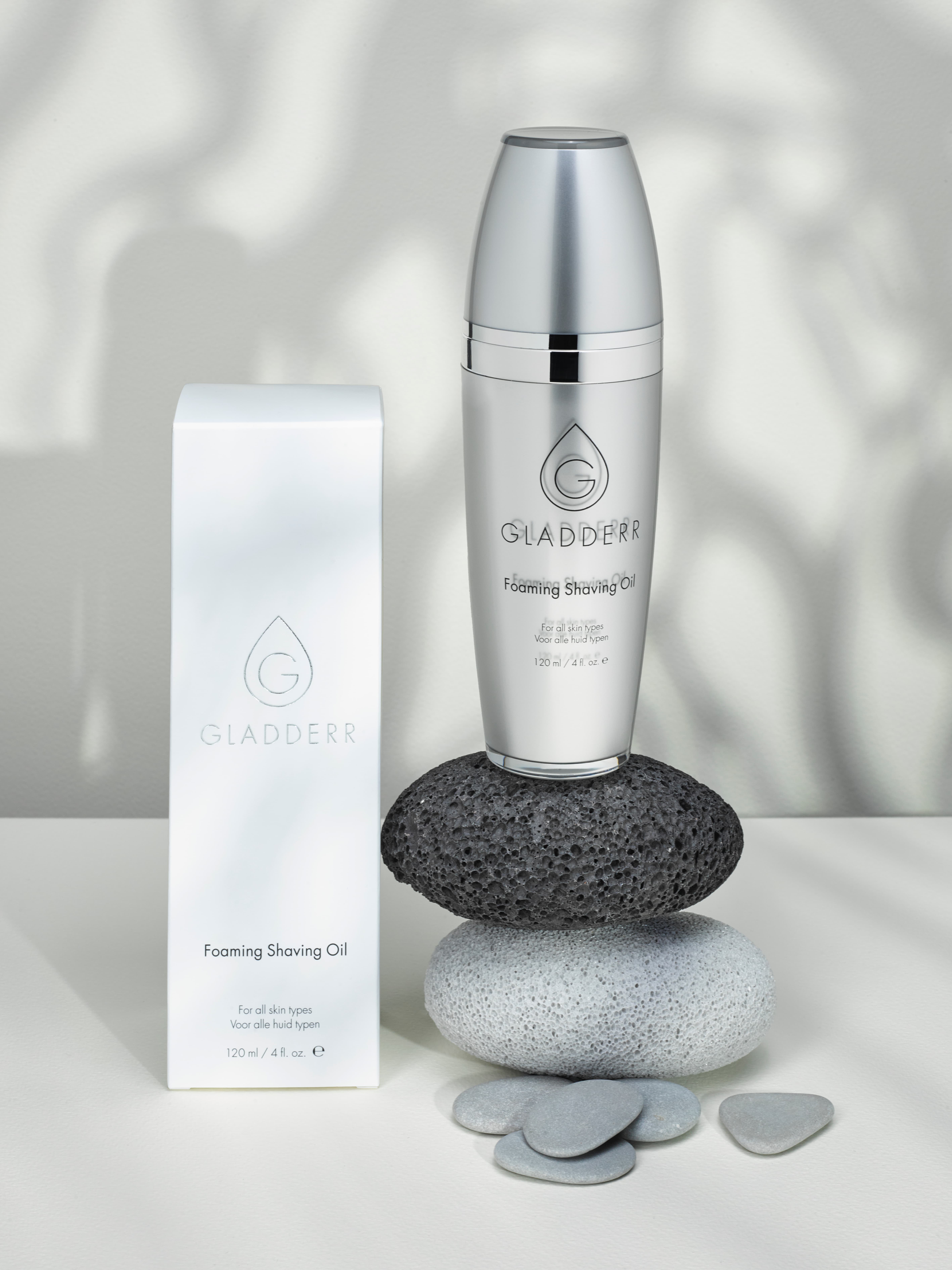 Gladderr Foaming Shaving Oil fles en doos elegant gepresenteerd op gladde stenen, met een rustgevende, schaduwrijke achtergrond die een spa-gevoel oproep. Gefotografeerd in de studio.
